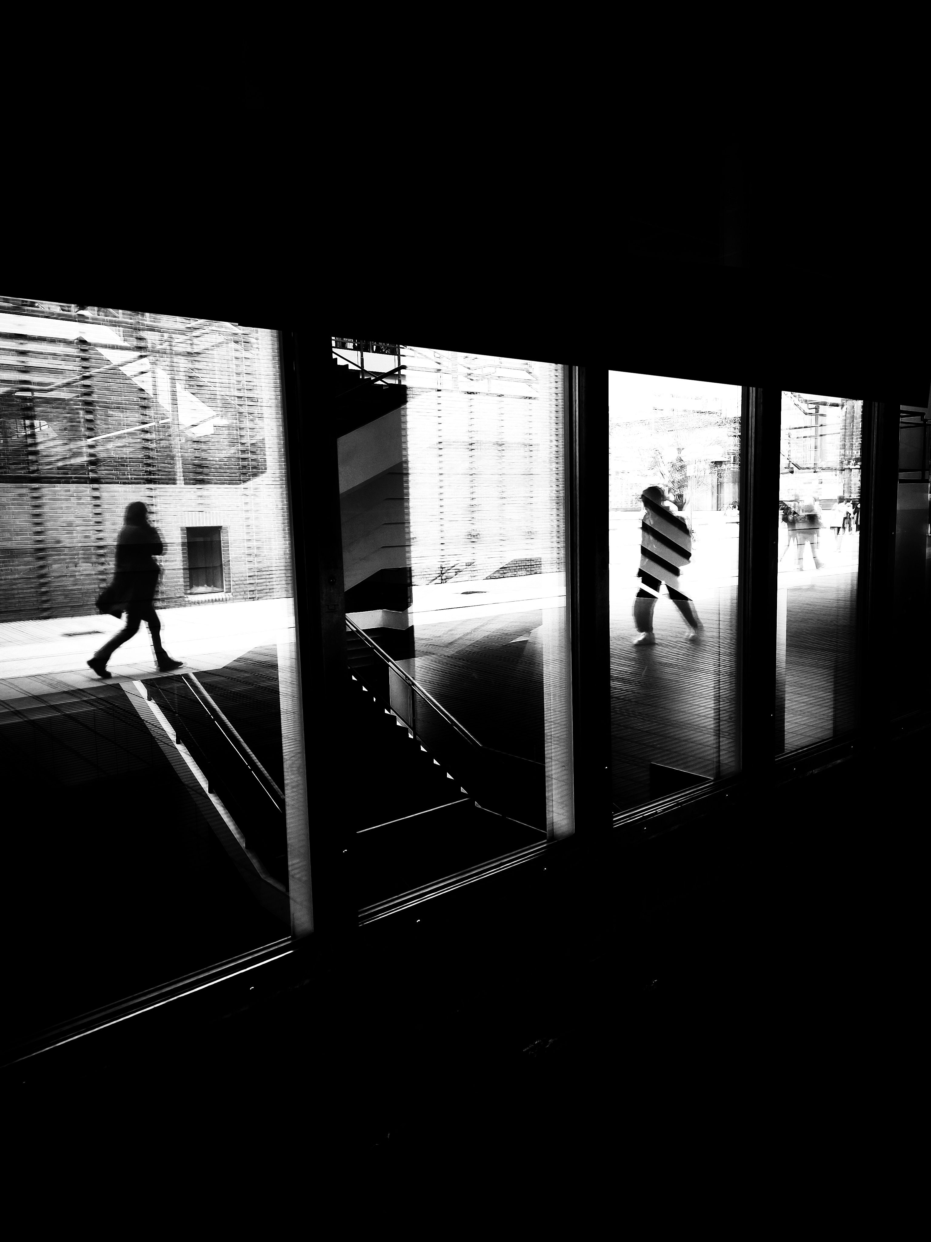 A black and white photo of people walking through a glass door · Free ...