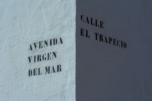 Textured building corner with street names in Spanish, showing intersection detail.