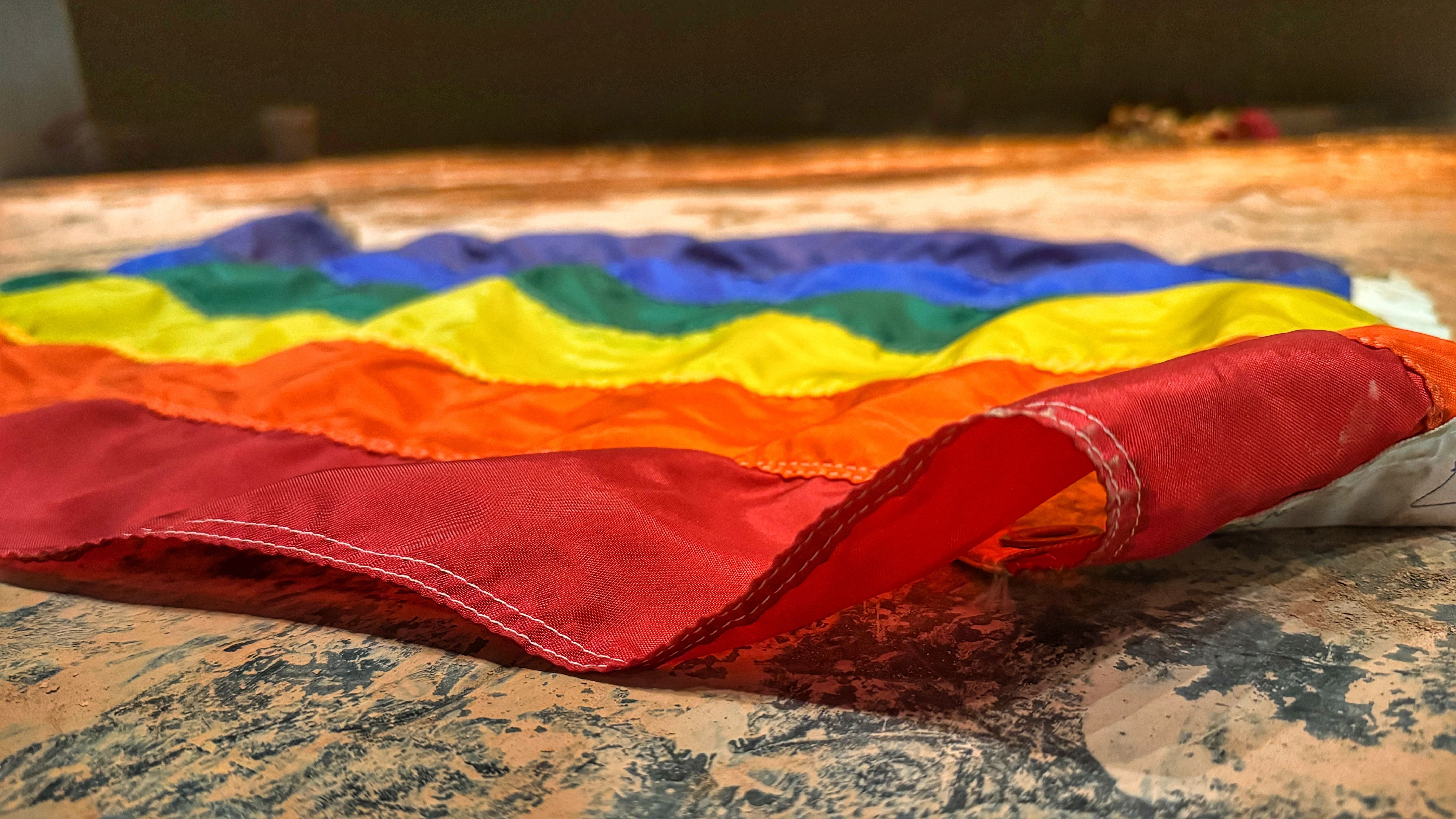 Imagen de archivo: Primer plano de una vibrante bandera del orgullo arcoíris descansando sobre una superficie texturizada.