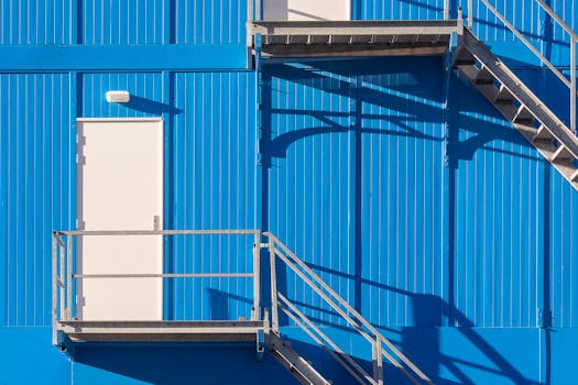 Minimalist industrial building with blue facade and metal stairs.