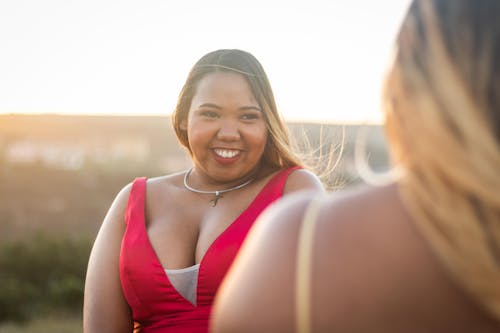 Free Happy stylish curvy black woman with unrecognizable girlfriend on street Stock Photo