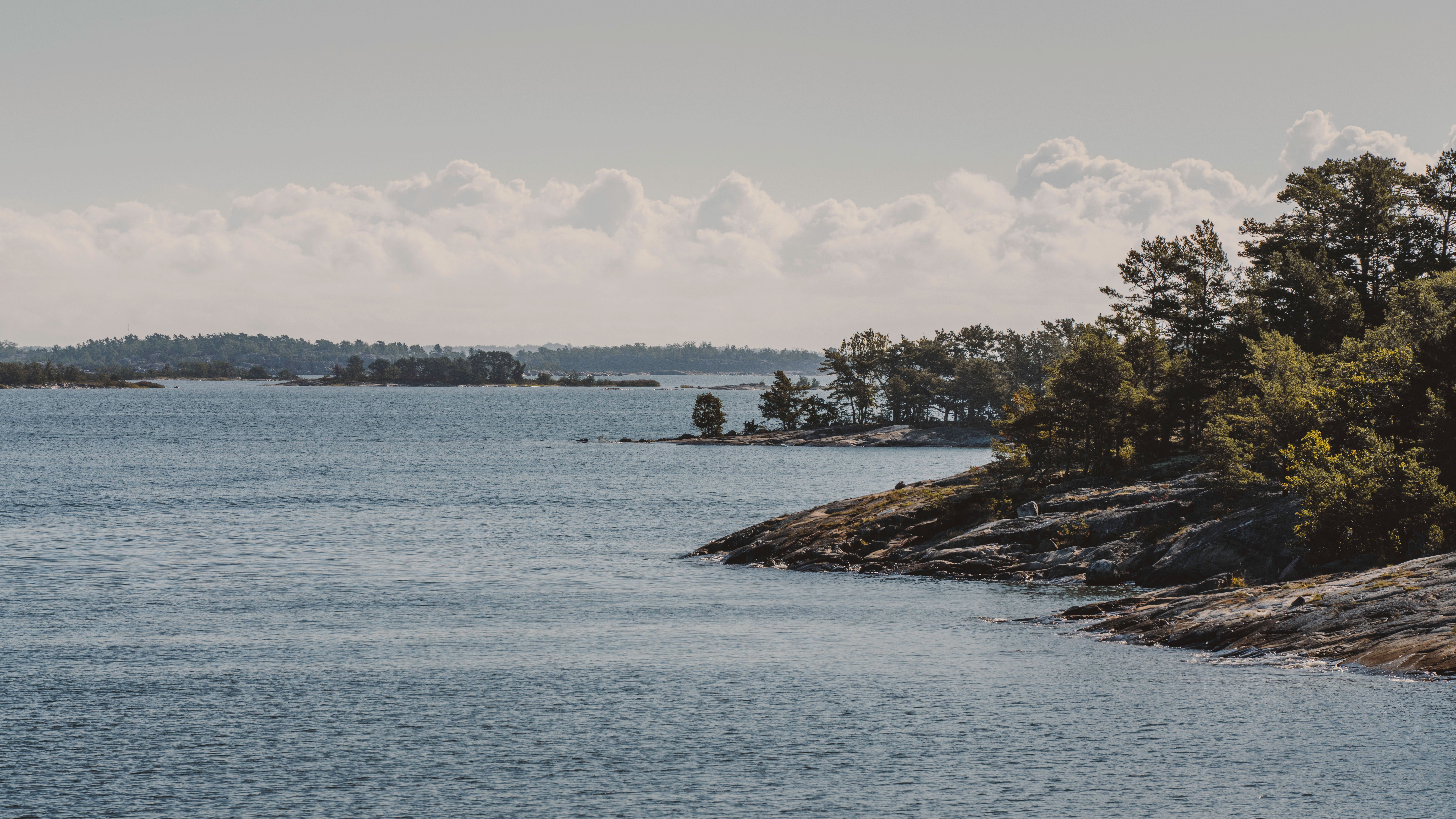 Breathtaking view of Turku Archipelago with lush trees and clear blue water. - Turku