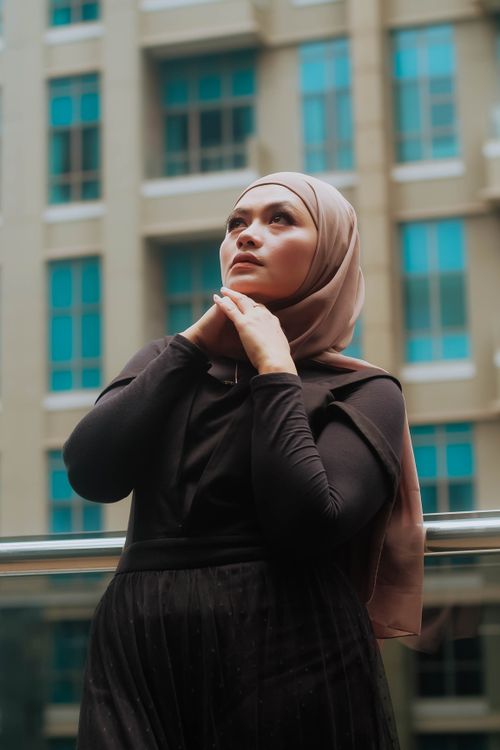 Free A woman in a pink hijab poses confidently outdoors against an urban backdrop. Stock Photo