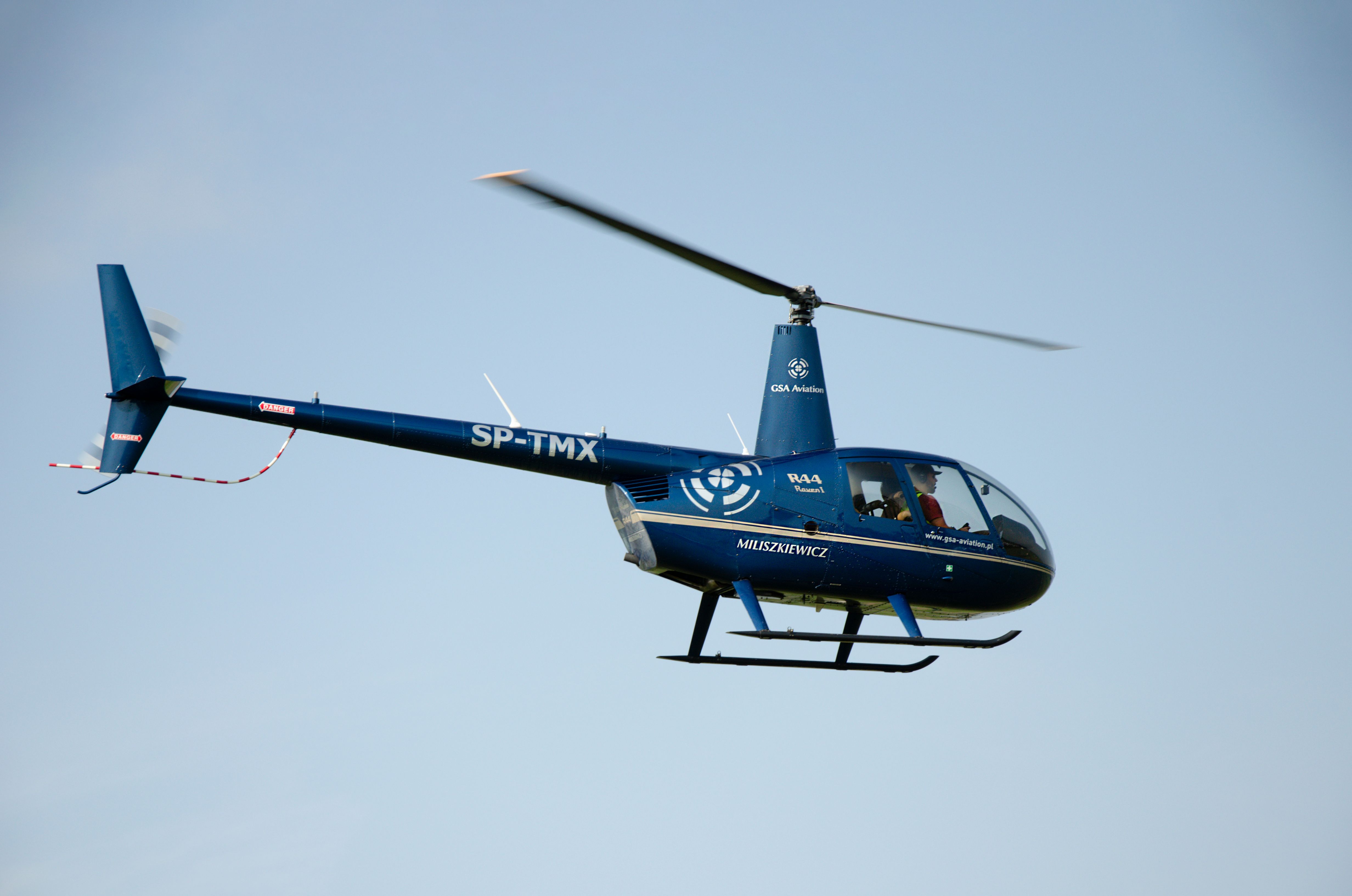 A blue helicopter soaring through a clear sky