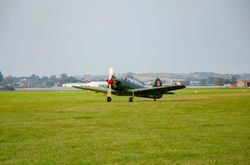 Free A classic military fighter jet on a grassy airstrip under a clear sky. Stock Photo