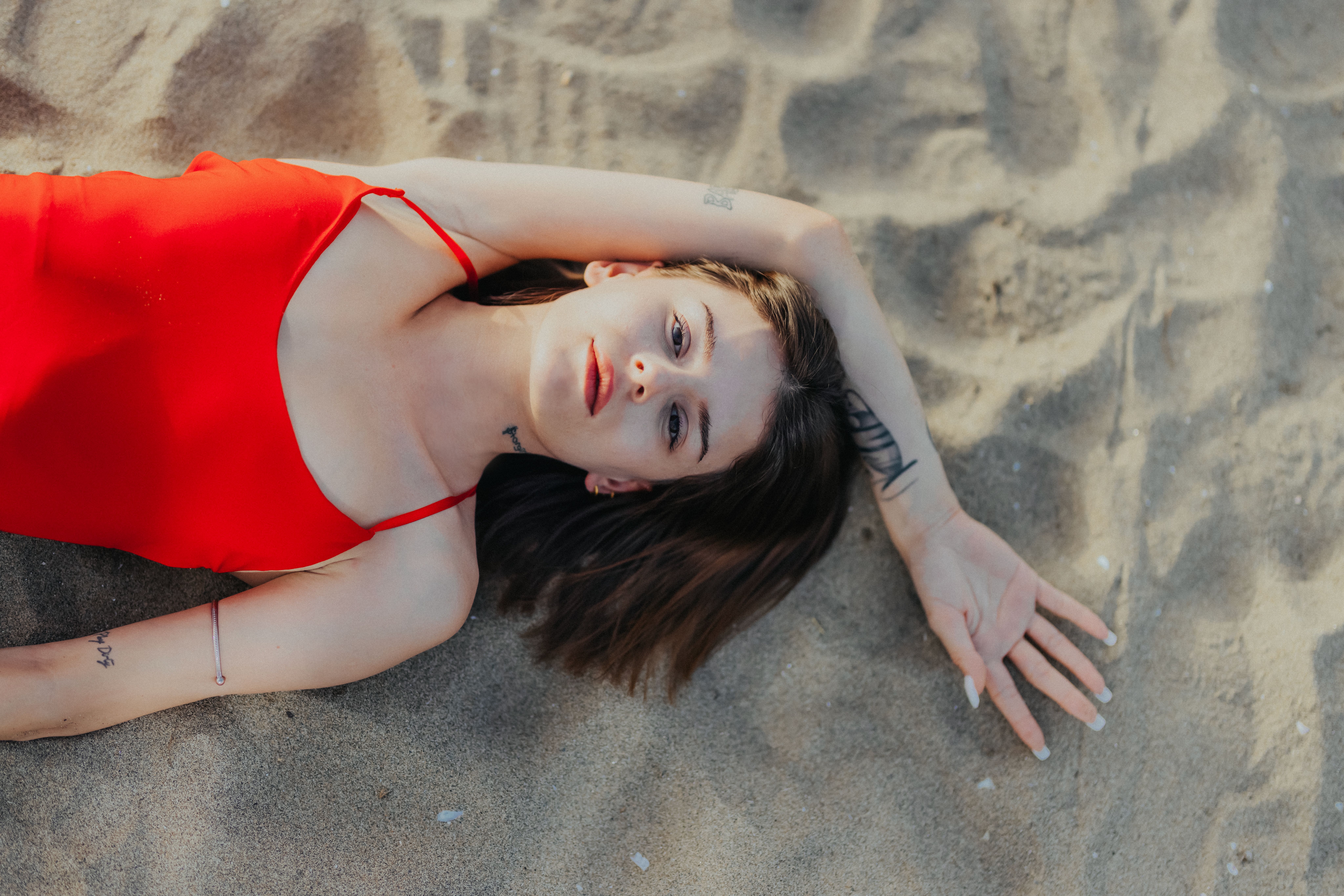 A woman laying on the sand in a red dress · Free Stock Photo