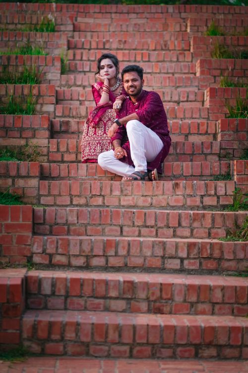 Free Couple in traditional attire sitting on brick steps outdoors, symbolizing love. Stock Photo