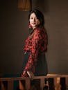 一位时尚优雅的女人在室内穿着红黑衬衫摆姿势，散发着自信