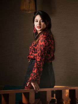 一位时尚优雅的女人在室内穿着红黑衬衫摆姿势，散发着自信