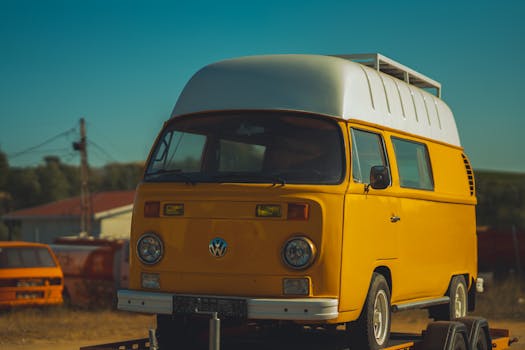 A classic yellow camper van parked outdoors under the sunset sky, evoking a retro travel vibe.