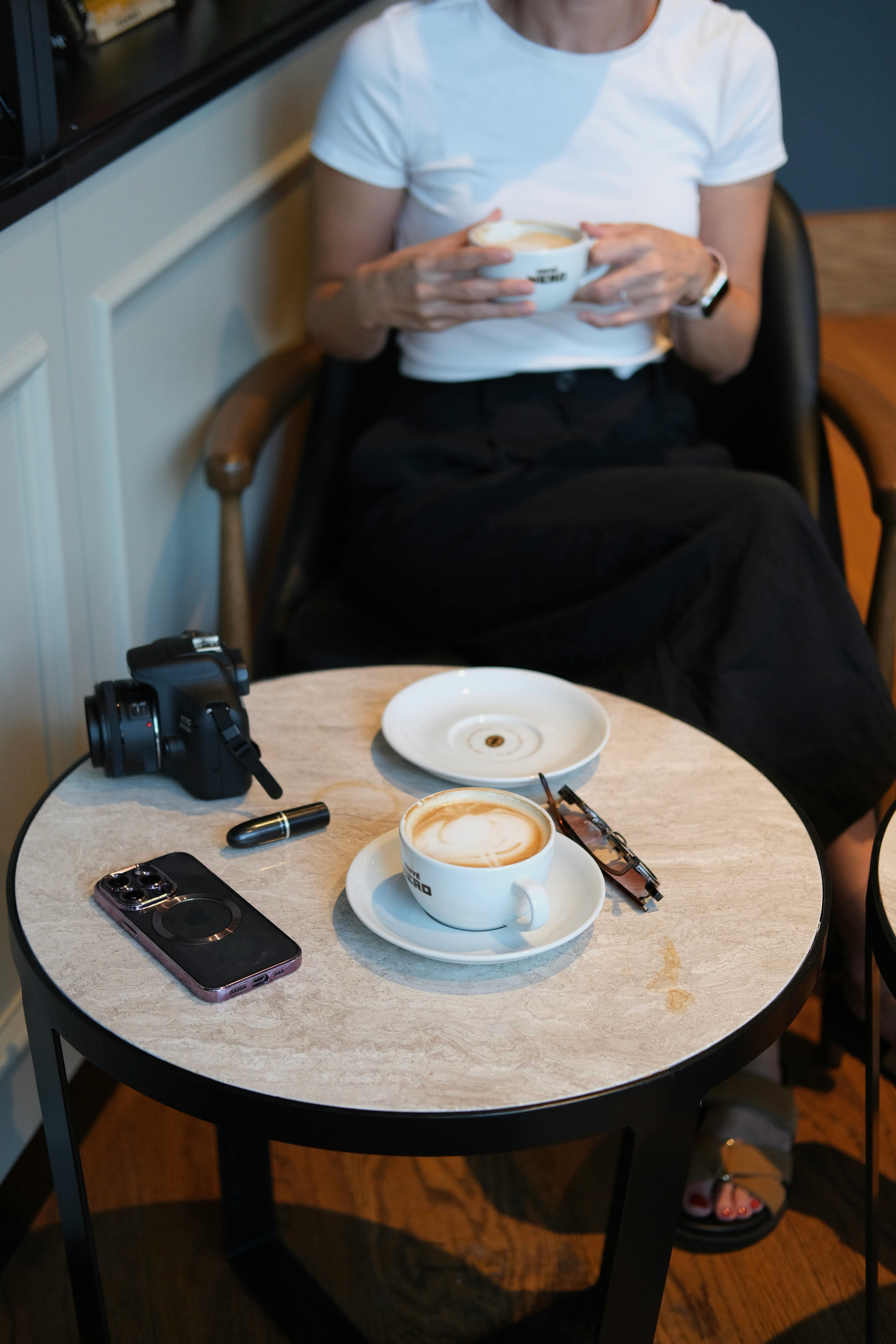 a woman sitting at a table with a cup of coffee