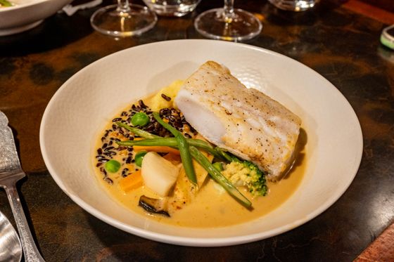 White fish fillet in golden coconut curry with black rice, green beans, broccoli, carrot and peas