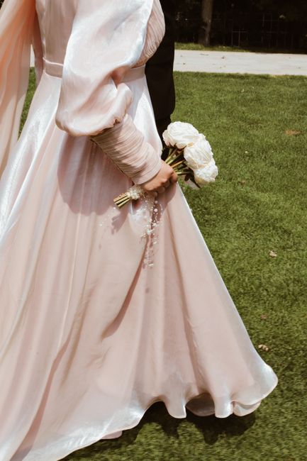 A bride in a beautiful gown holding white roses, captured outdoors at a wedding.