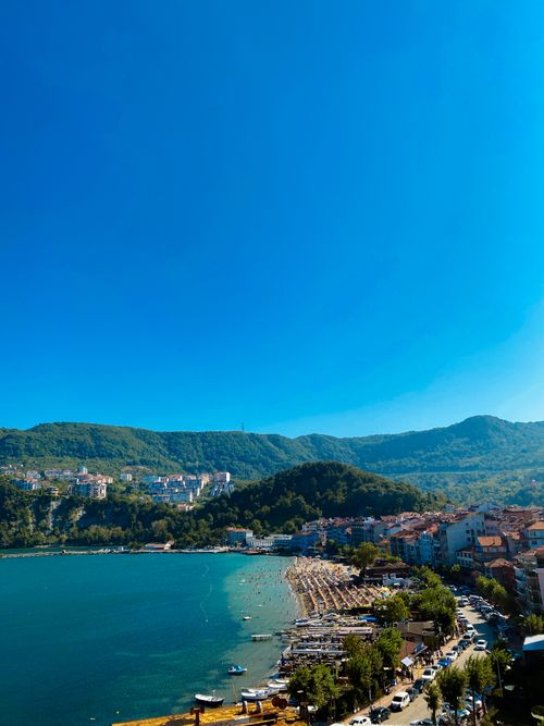 Free Aerial view of a picturesque beach town with turquoise waters and lush hills. Stock Photo