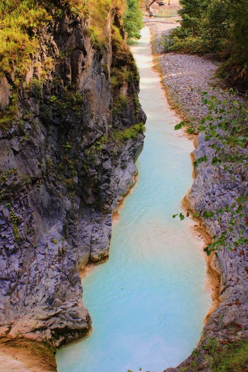 Free A narrow turquoise river flowing through a rocky gorge surrounded by greenery. Stock Photo