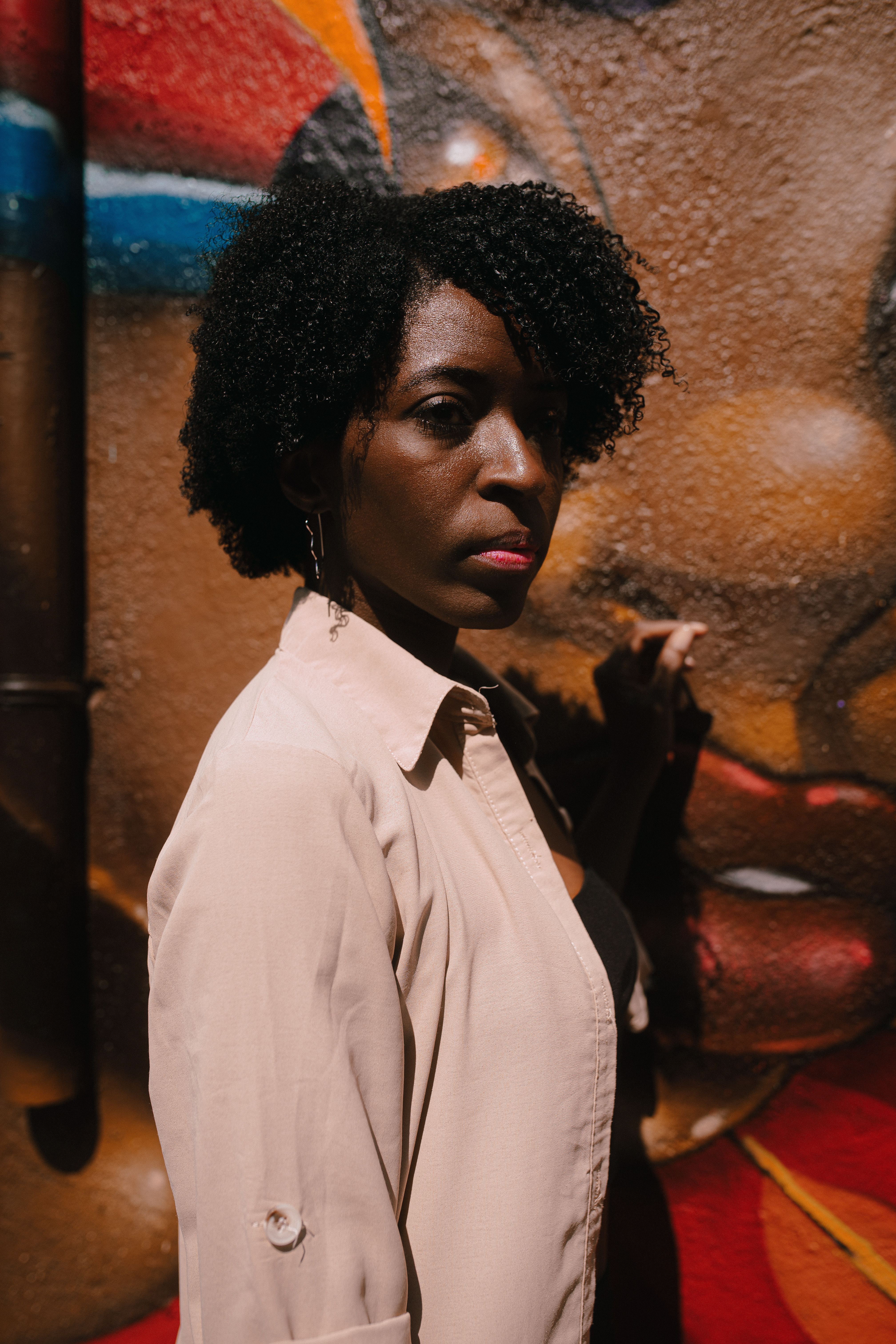 A woman with afro hair standing in front of a wall · Free Stock Photo
