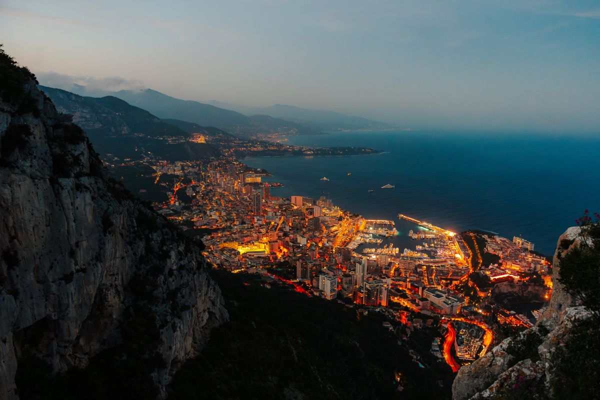 Monaco glittering at dusk between the sea and the cliffs