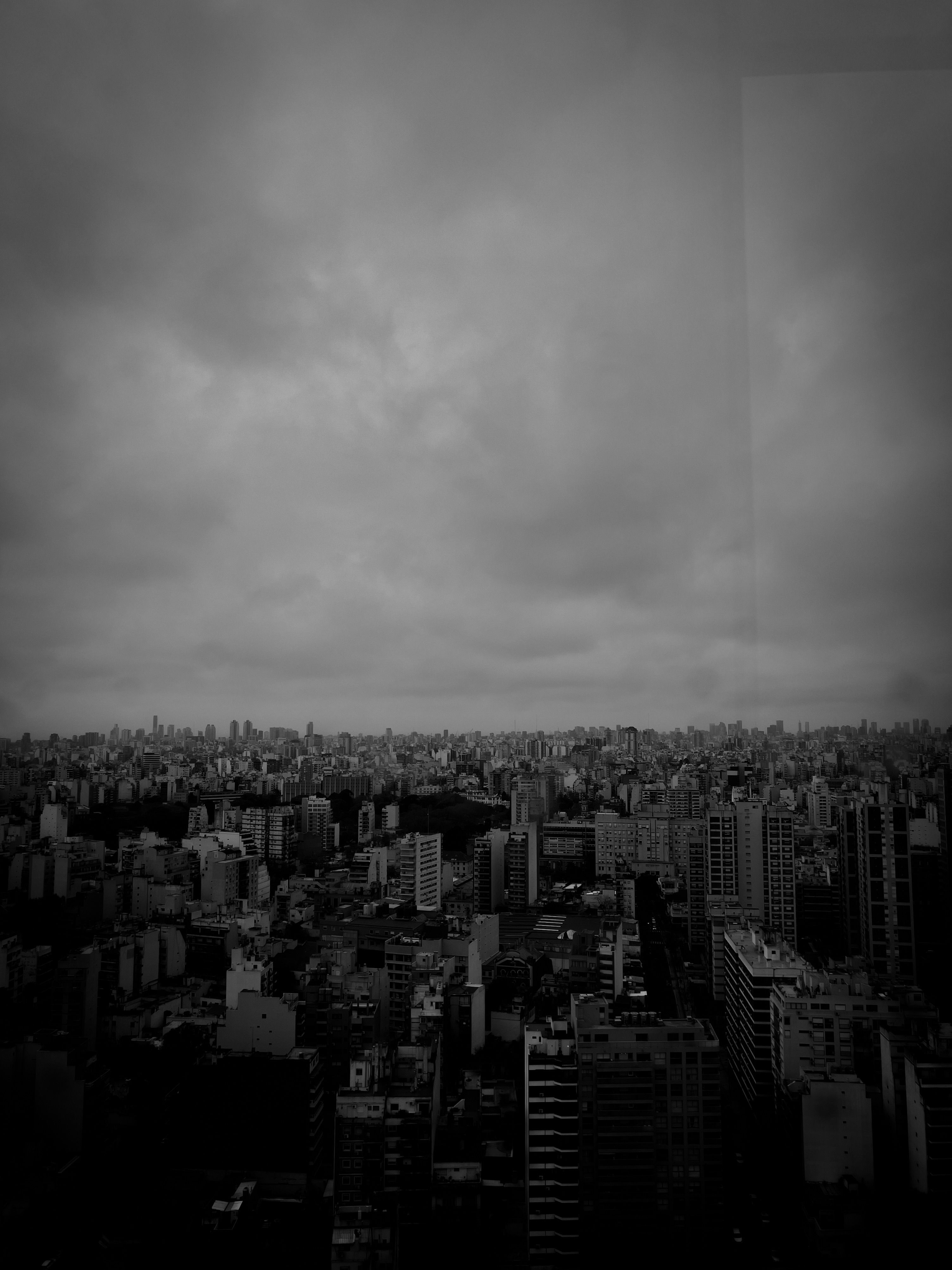 A black and white photo of a city with cloudy skies · Free Stock Photo