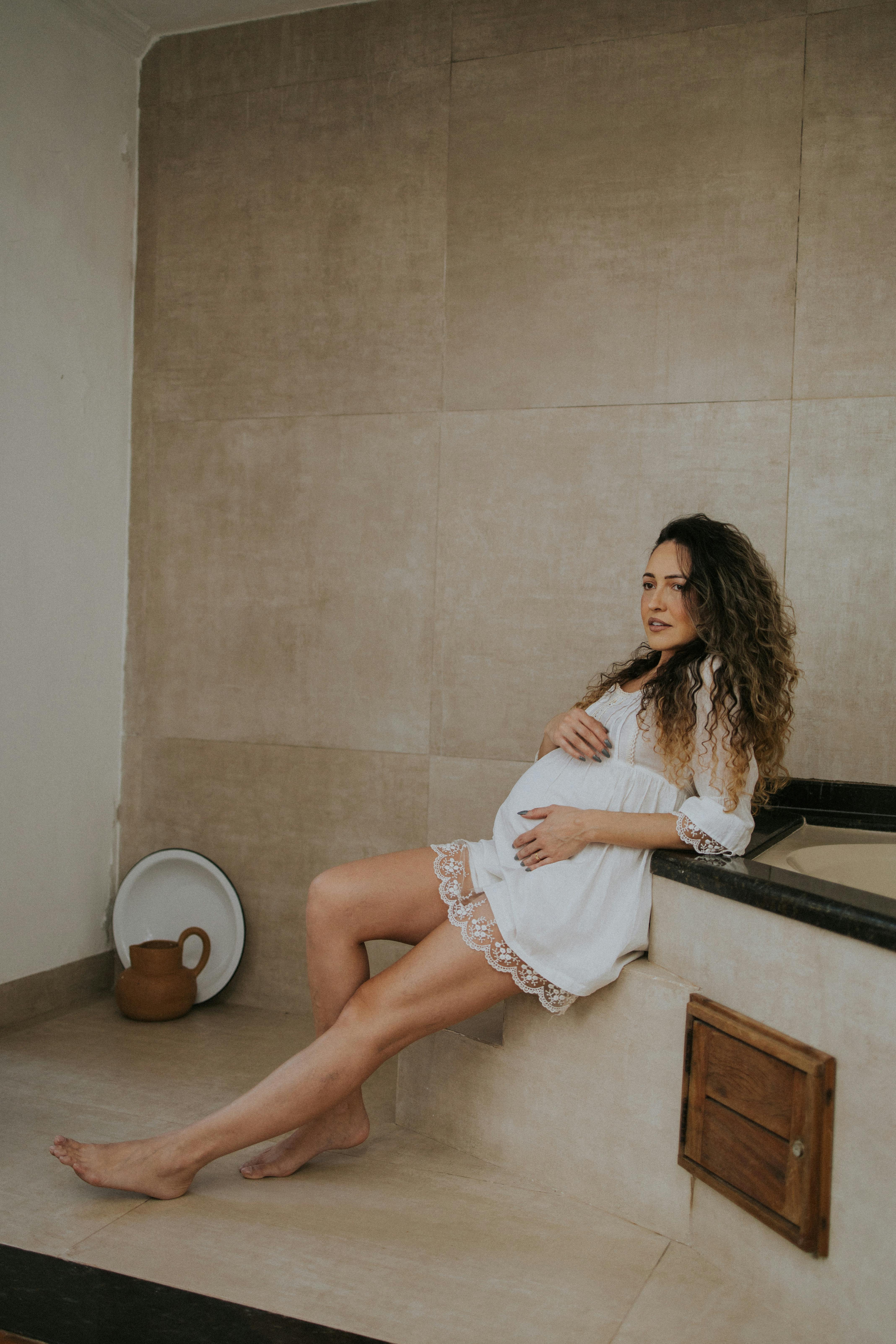 a pregnant woman sitting in a bathtub