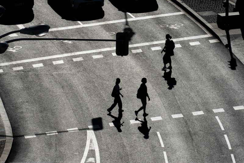 A high angle black and white view of pedestrians crossing an urban street in Madrid, Spain.