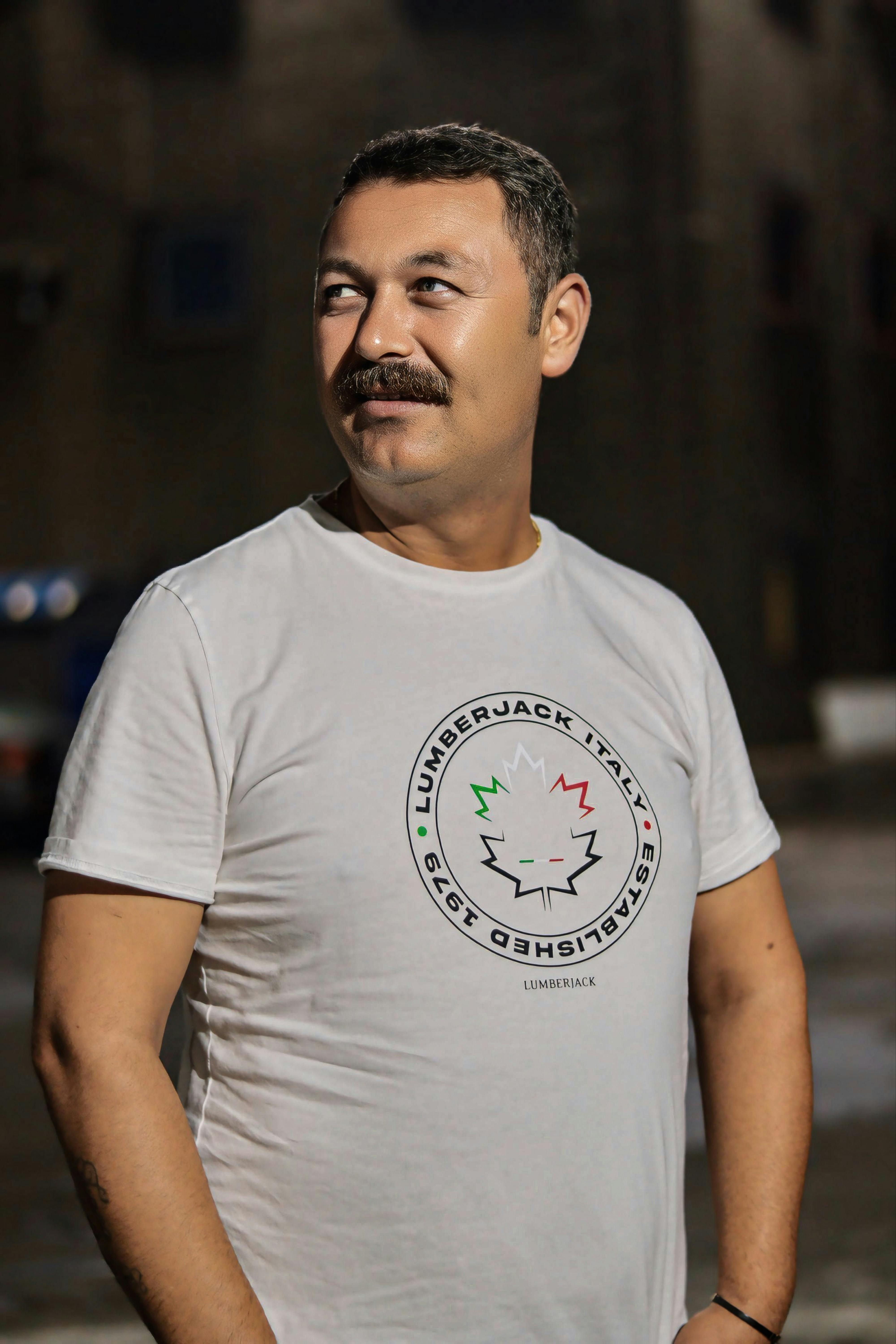 a man in a white t shirt standing in front of a building