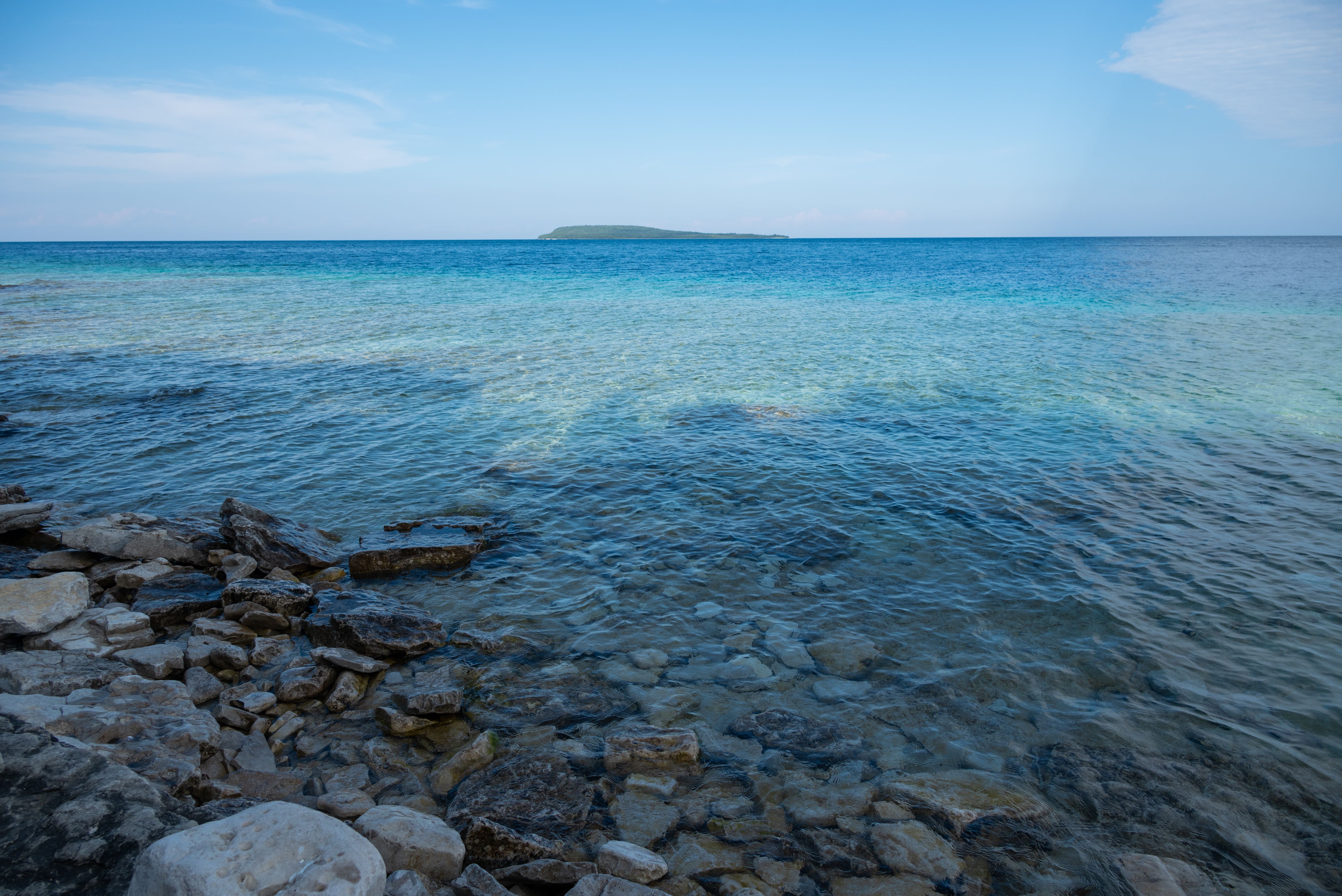 Crystal clear water and rocky shoreline at Tobermory, Ontario, offering a tranquil seascape view.