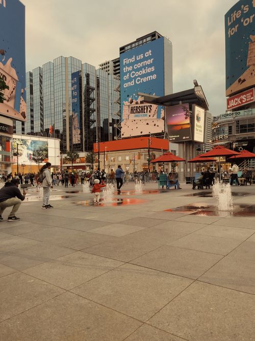 Free Lively urban plaza with fountains and billboards at Dundas Square, Toronto. Captures the city's dynamic atmosphere. Stock Photo