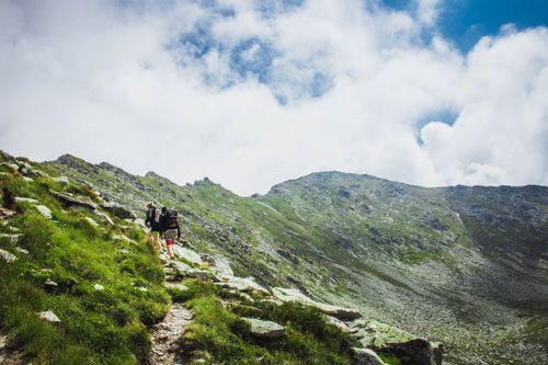 Free Two hikers explore lush green mountains under a bright sky in Romania, capturing the essence of adventure. Stock Photo