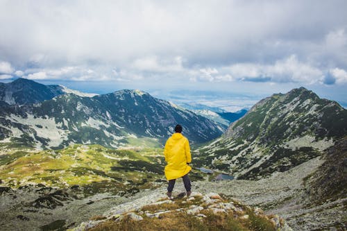 Man Standing on a Hill Under White Clouds