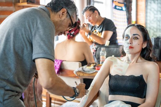 Artists prepare women with intricate Catrina makeup for a cultural celebration in CDMX.