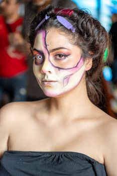 A young woman adorned with Catrina makeup, showcasing Mexican culture at a festival in México City.