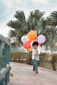 A cheerful child runs in a park holding colorful balloons. Capturing joy.