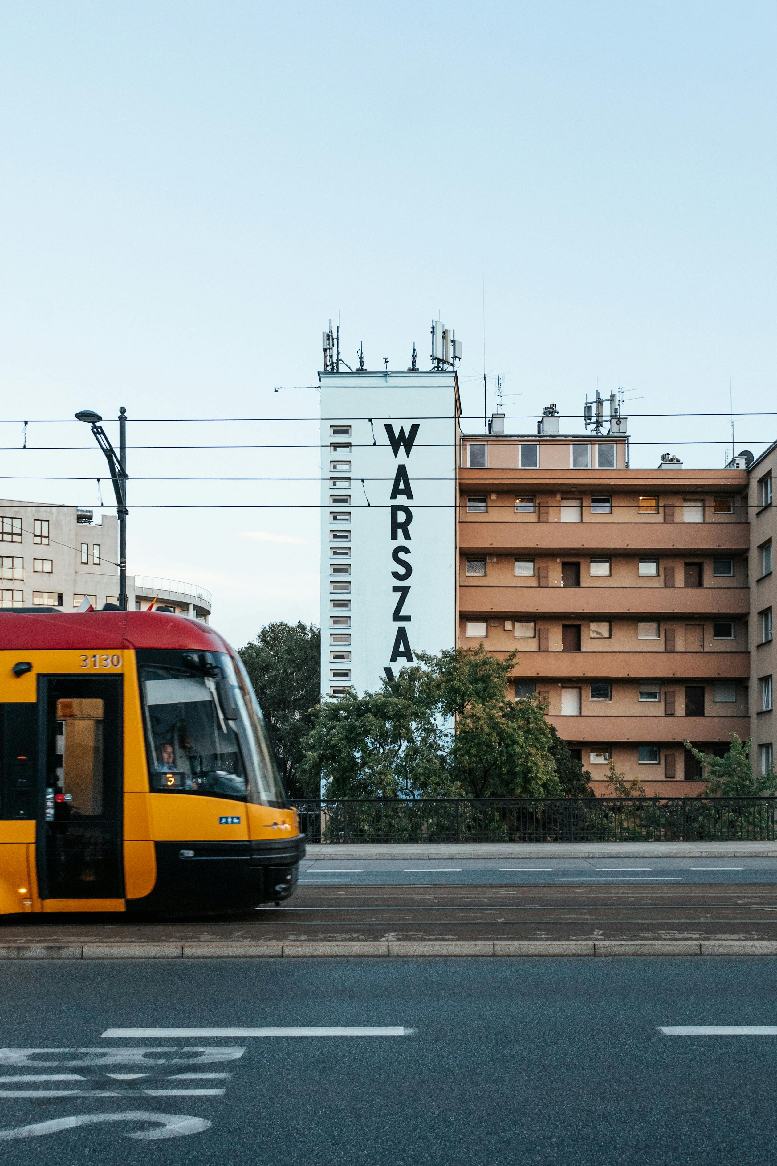 Vibrant cityscape of a tram passing by buildings in Warsaw, Poland.