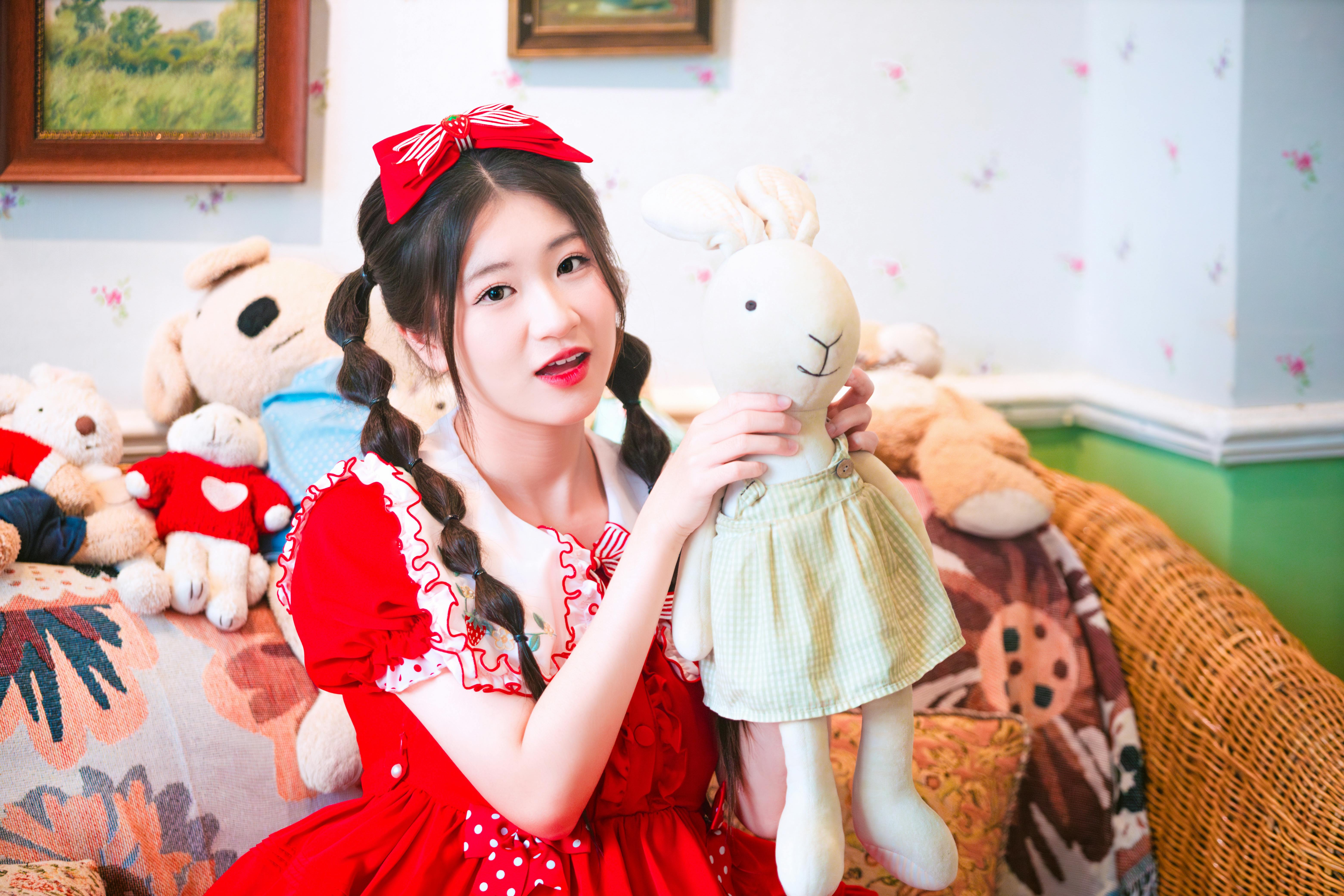 a woman in a red dress holding a stuffed animal