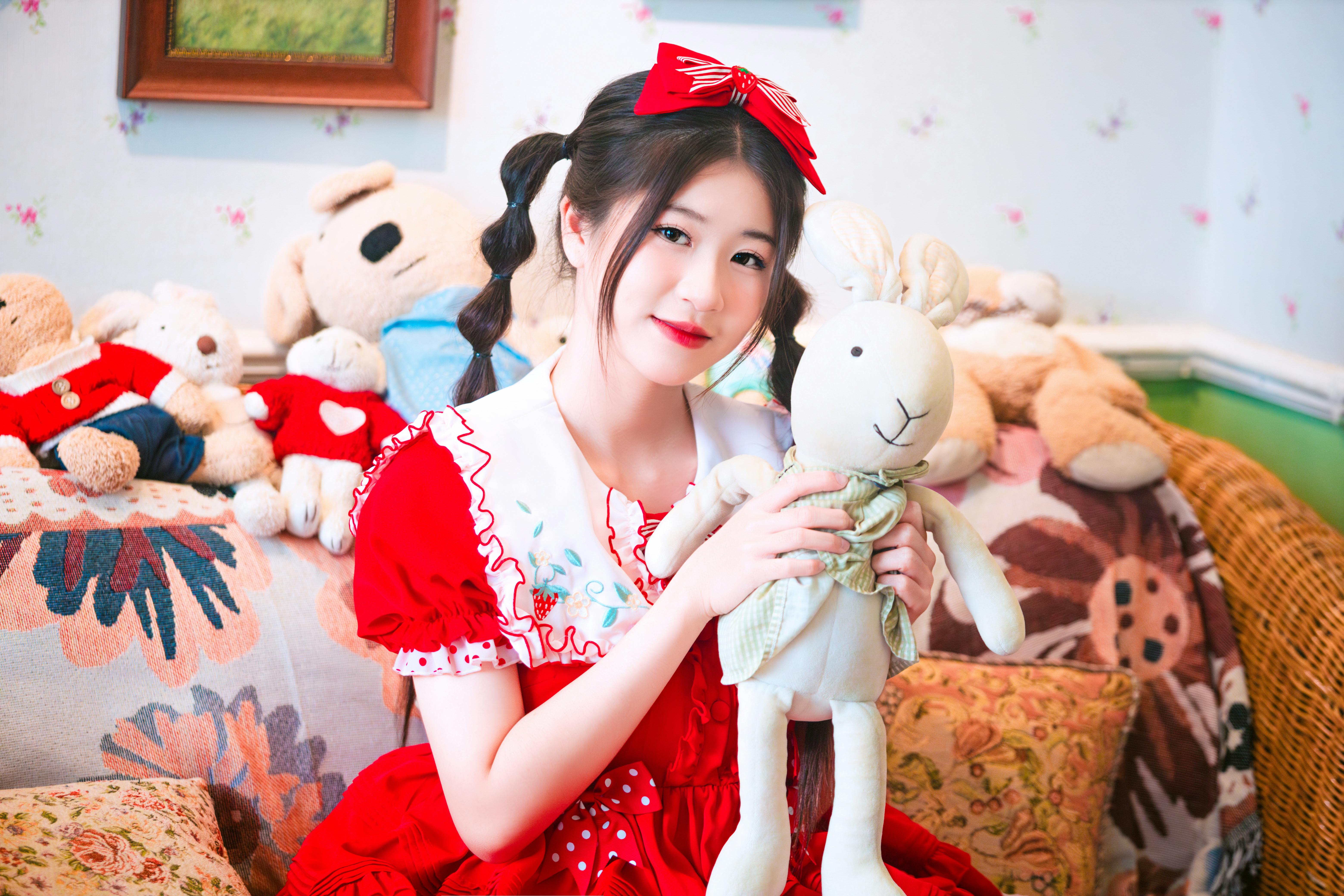 a woman in a red dress holding a teddy bear