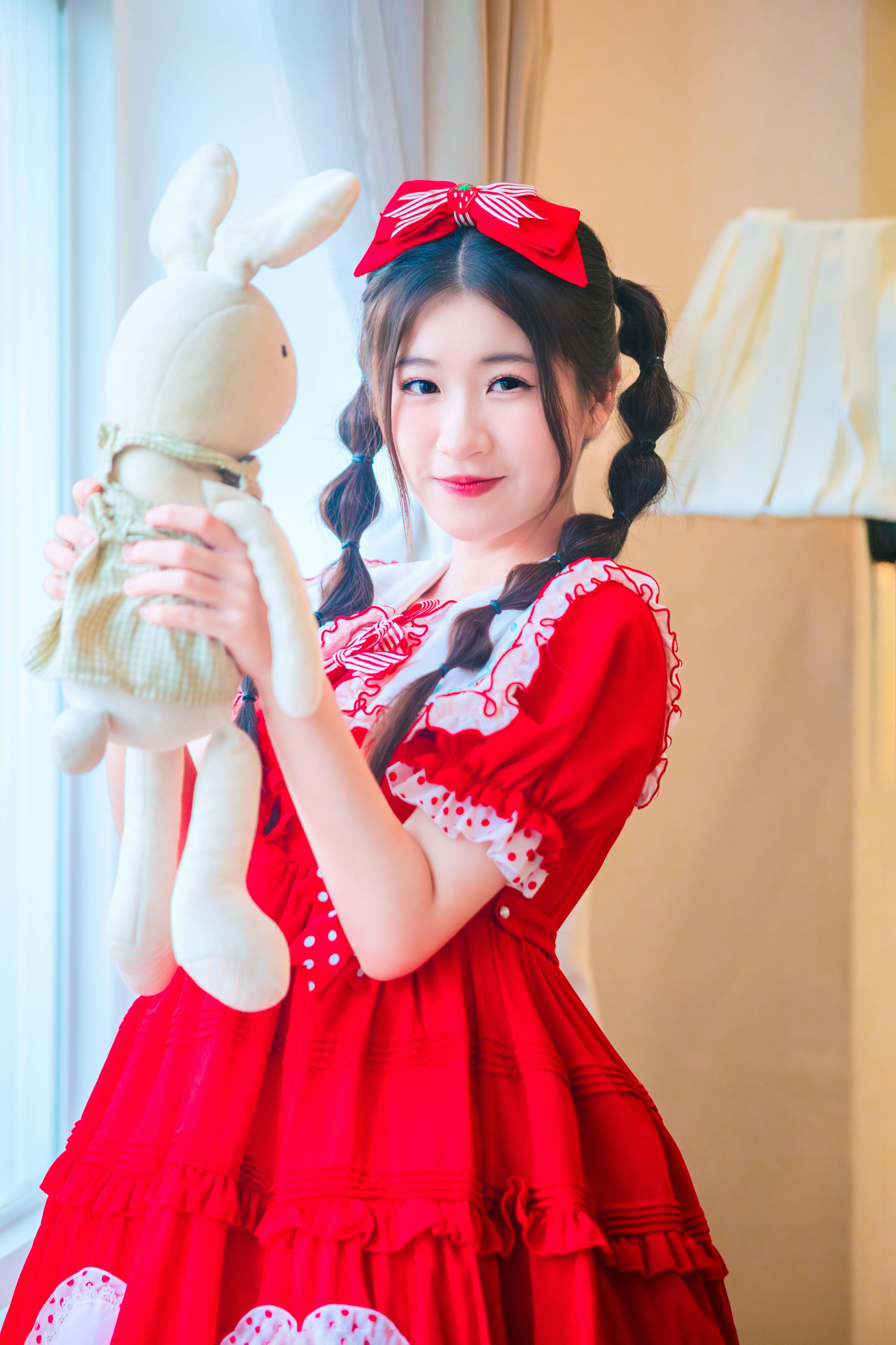 a woman in a red dress holding a stuffed animal