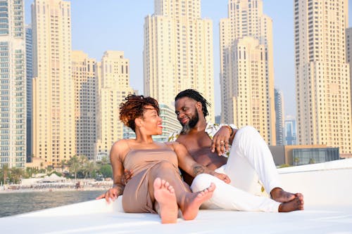 Couple enjoying a sunny day on a yacht with the iconic Dubai Marina skyline in the background.
