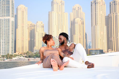 A couple enjoys a sunny day on a yacht with the iconic Dubai Marina skyline in the background.