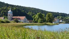 Tranquil view of a rural church and lake in Bourgogne-Franche-Comté, France.
