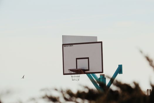 A solitary basketball hoop stands against a clear sky, evoking a serene, vintage vibe.