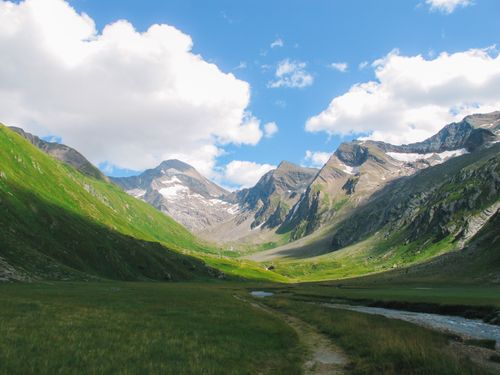 Free Breathtaking view of a serene alpine valley with mountains, snow, and clear skies. Stock Photo