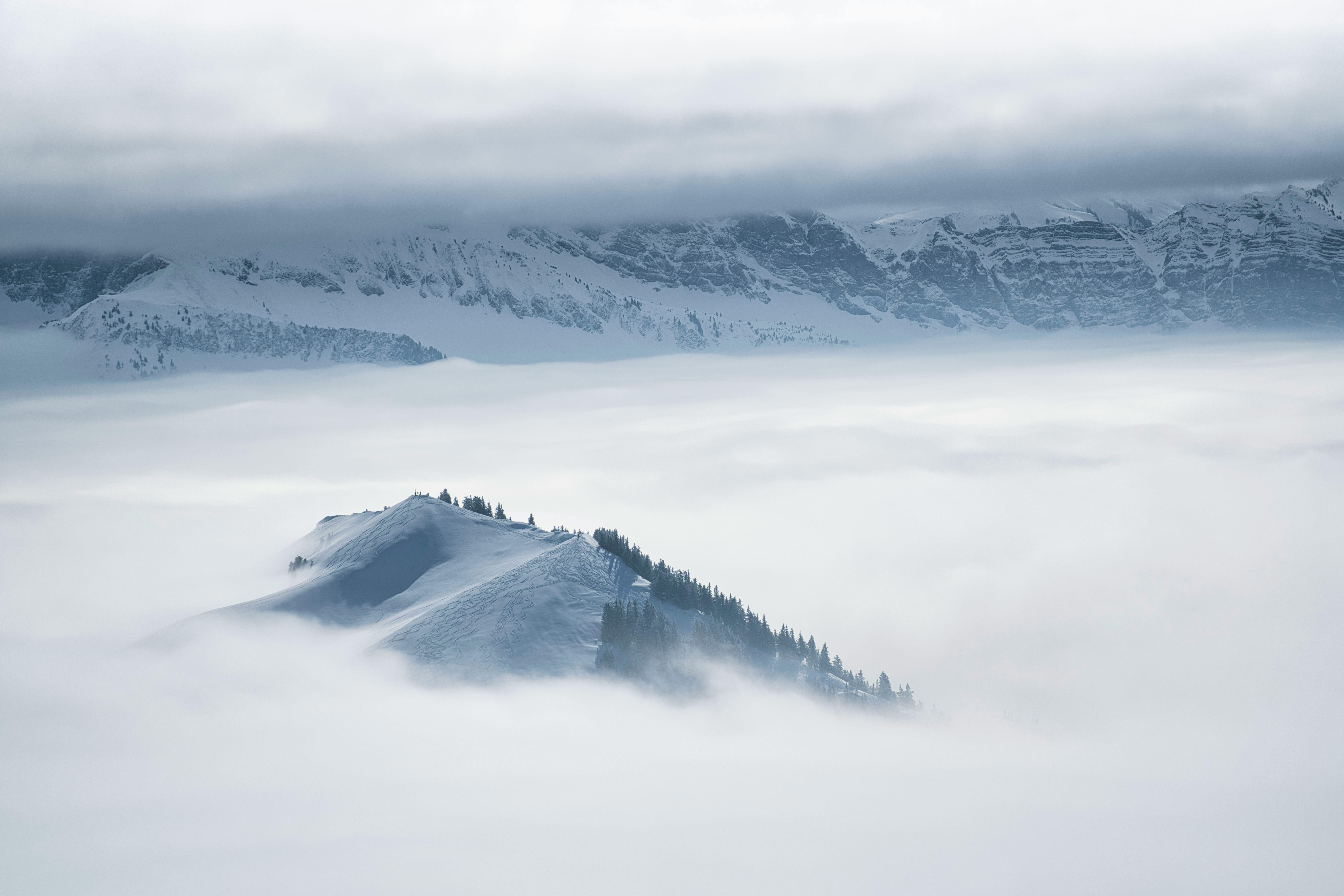 Majestic snow-covered mountain peak surrounded by fog in a serene winter landscape.