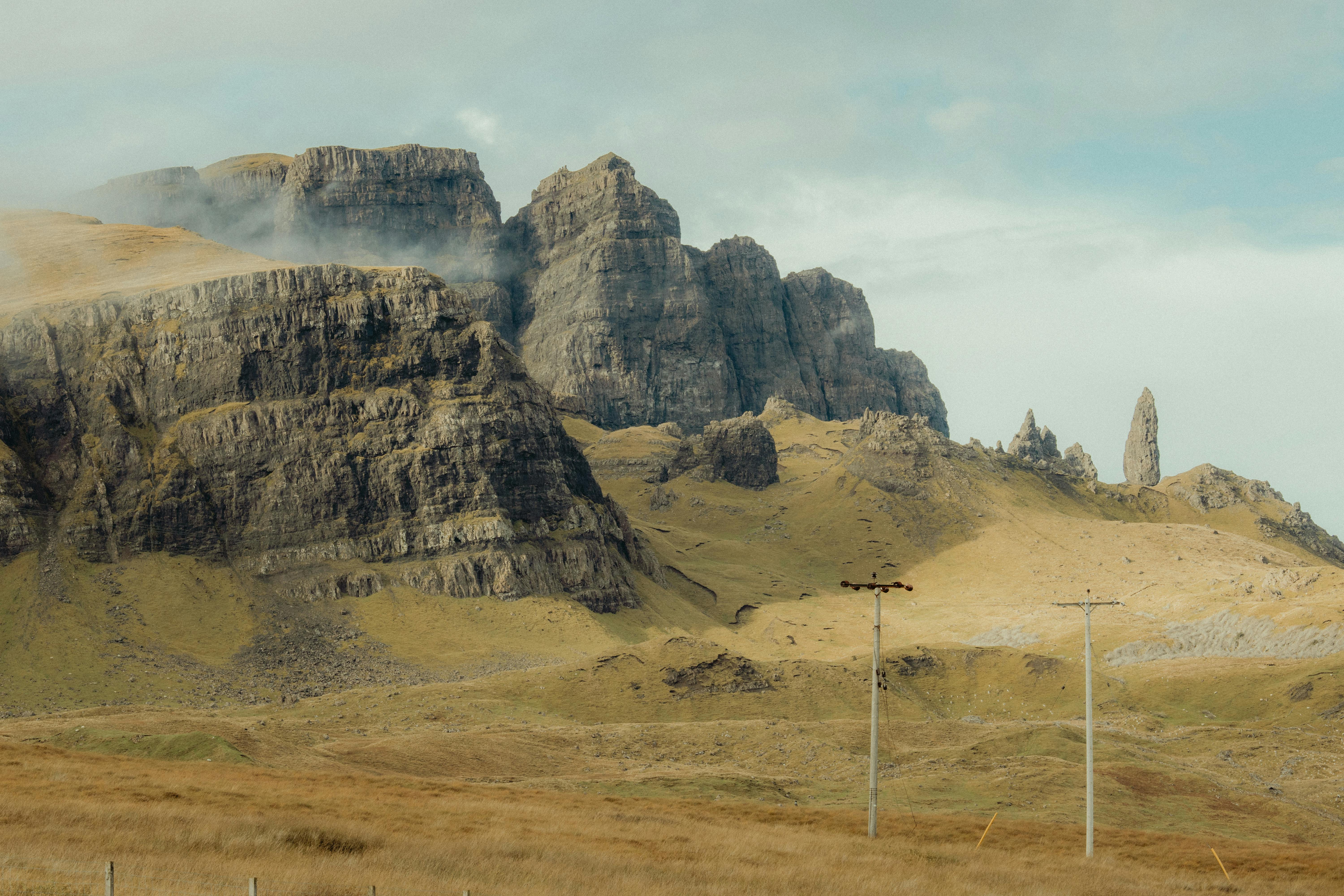 Majestic rocky landscape of the Scottish Highlands under a cloudy sky, featuring misty cliffs and natural formations.