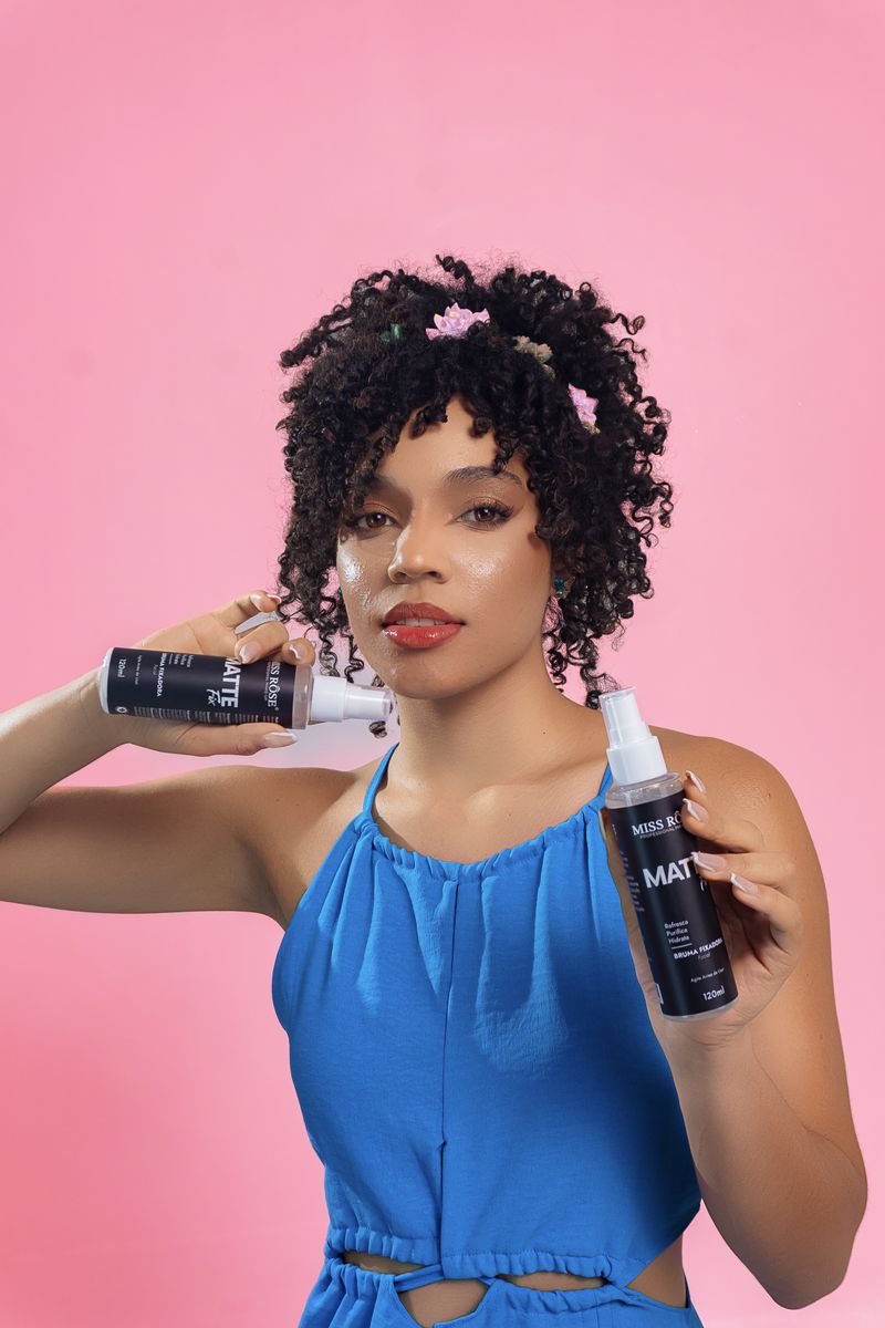 Mujer con rizos naturales sosteniendo productos champú para cabello rizado sin sulfatos