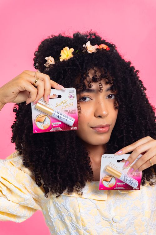 Free A cheerful young woman displays eyebrow enhancers against a vibrant pink backdrop. Stock Photo