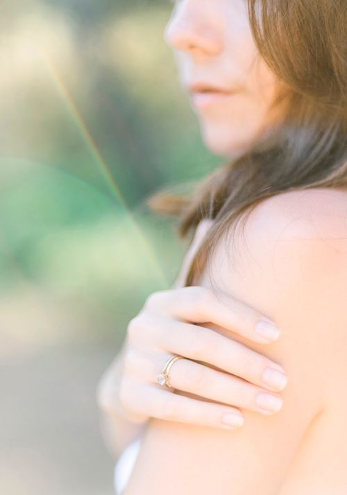 Free Soft-focus portrait of a young woman in sunlight, gently holding her shoulder outdoors. Stock Photo