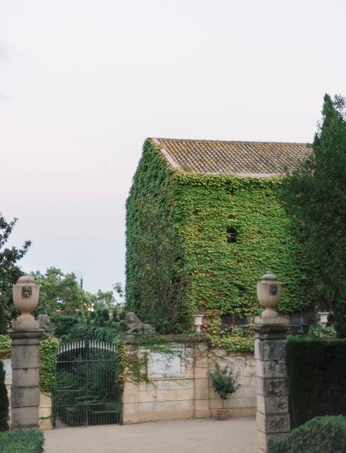 A serene ivy-covered stone building surrounded by lush gardens and ancient architecture.