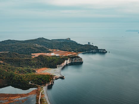 A stunning aerial view of a rugged coastline meeting the vast sea under a cloudy sky.