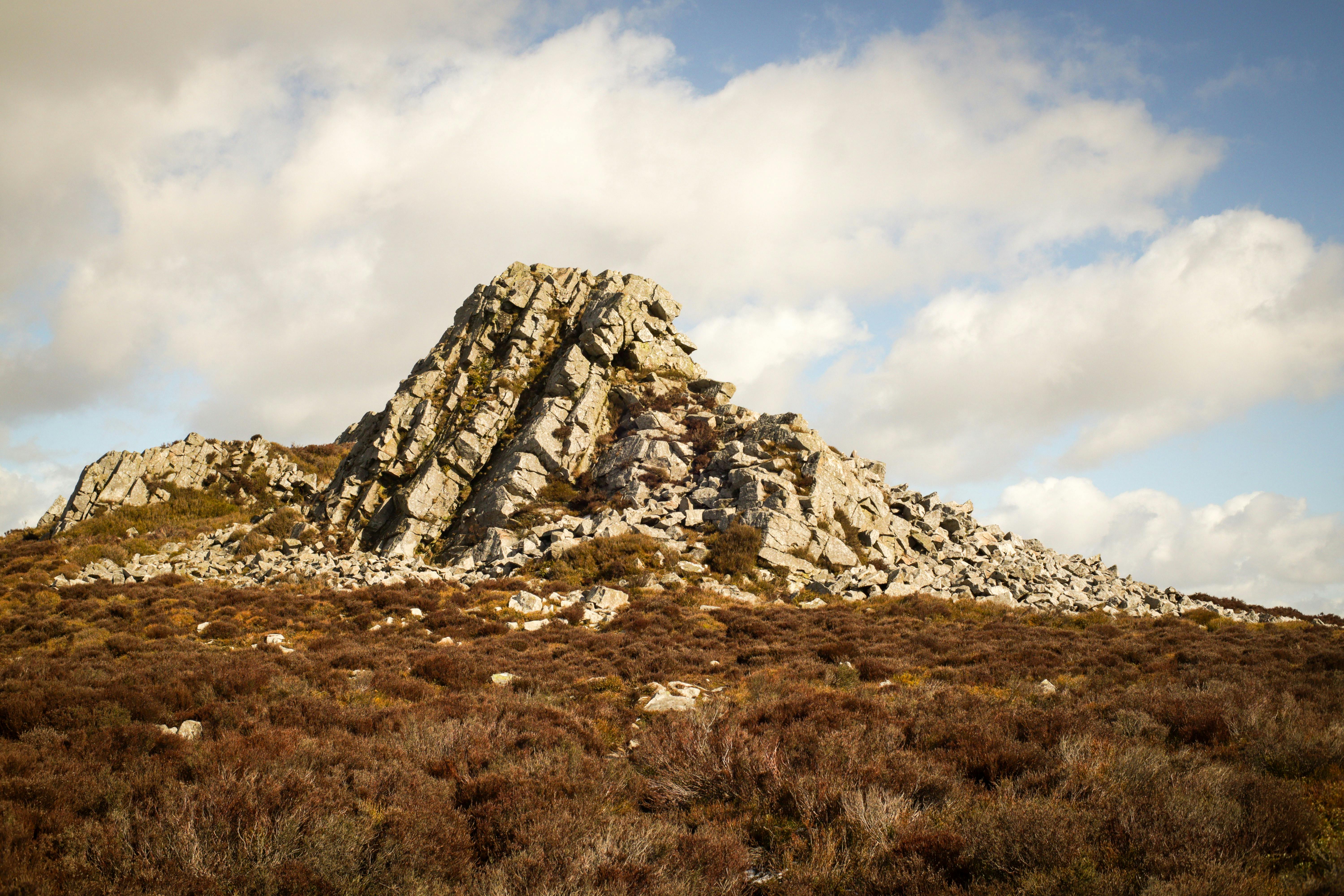 Scenic view of the rugged rock formation at Stiperstones surrounded by heathland under a vibrant sky.