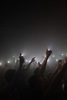 Silhouettes of concert attendees raising lights during a night performance in Minsk.